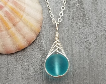 May include: A silver chain necklace with a turquoise blue glass bead pendant wrapped in silver wire.