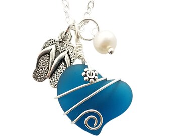 May include: A teal blue glass heart pendant necklace with silver wire wrapping, a silver flip-flop charm, and a white pearl charm.