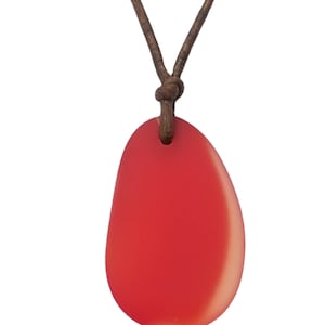 May include: A red pendant necklace with a smooth, oval-shaped stone. The pendant is suspended from a brown leather cord, knotted at the top. The stone has a gradient effect, transitioning from a deeper red to a lighter shade.