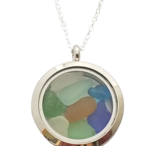 May include: A silver locket necklace with a clear glass insert containing small pieces of sea glass in shades of blue, green, and white.