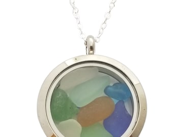 May include: A silver locket necklace with a clear glass insert containing small pieces of sea glass in shades of blue, green, and white.
