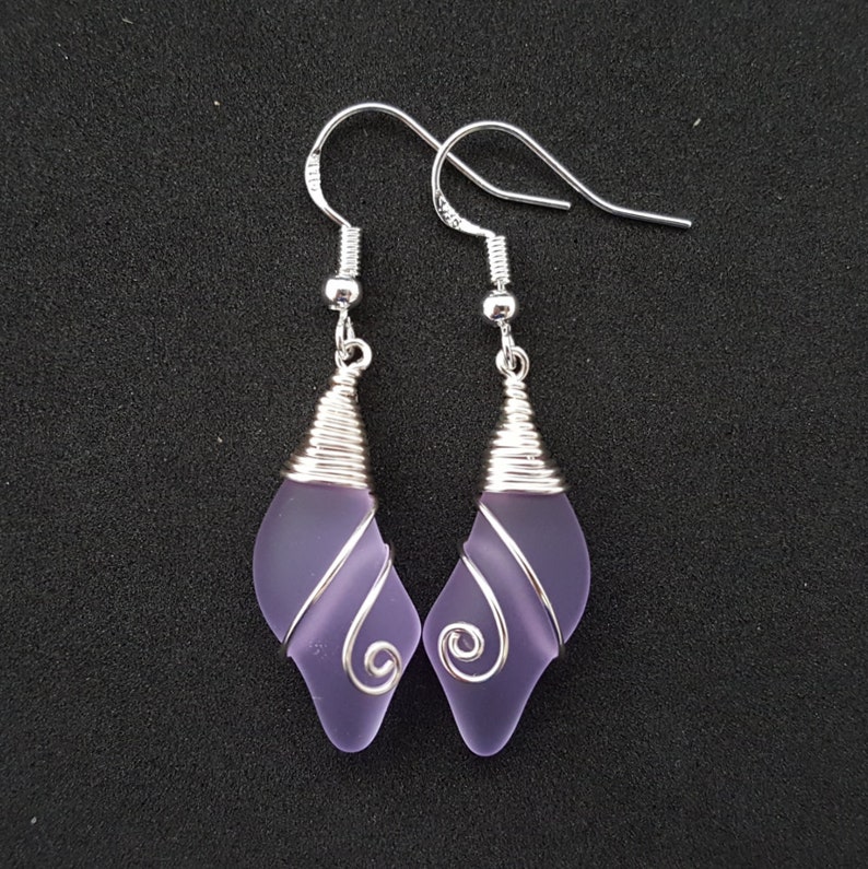 May include: A pair of silver dangle earrings with lavender glass teardrop-shaped beads wrapped in silver wire.