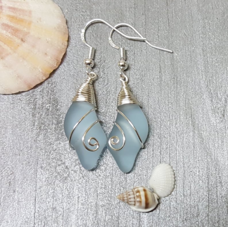 May include: A pair of silver wire wrapped earrings with light blue glass teardrop shaped stones.