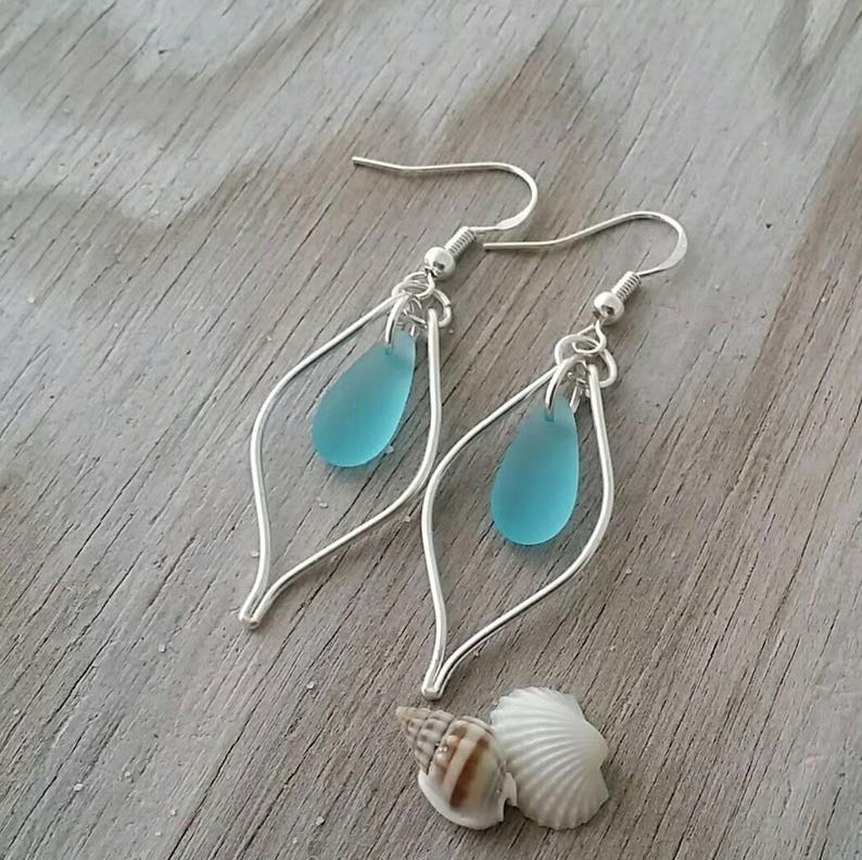 May include: Silver dangle earrings with a teardrop shaped blue glass bead hanging from each earring.