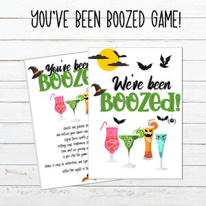 Può includere: Due stampabili di giochi per feste a tema Halloween. Il testo "YOU'VE BEEN BOOZED GAME!" è in alto. Una carta dice "You've been BOOZED!" e l'altra dice "We've been BOOZED!" con illustrazioni di cocktail e decorazioni di Halloween.