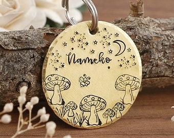 May include: Brass dog tag with a mushroom and moon design. The tag is engraved with the name "Nameko" and has a star pattern.