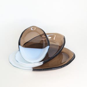 Puede incluir: Un juego de tres tazas de cerámica con un acabado mate moteado. Las tazas son de color crema, marrón claro y marrón oscuro. Cada taza tiene un diseño sencillo y un asa redondeada.