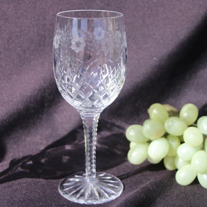 May include: A clear glass wine glass with a cut crystal design and etched floral pattern. The glass has a long stem and a wide bowl.