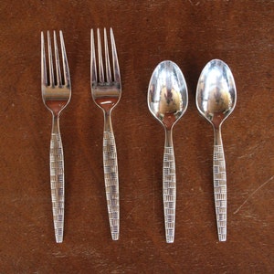 May include: Four pieces of silverware, two forks and two spoons, with a woven pattern on the handles. The silverware is silver in color and has a polished finish.