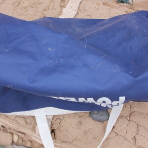 May include: A blue, canvas duffel bag with white straps and the word "POWER" printed on the side.