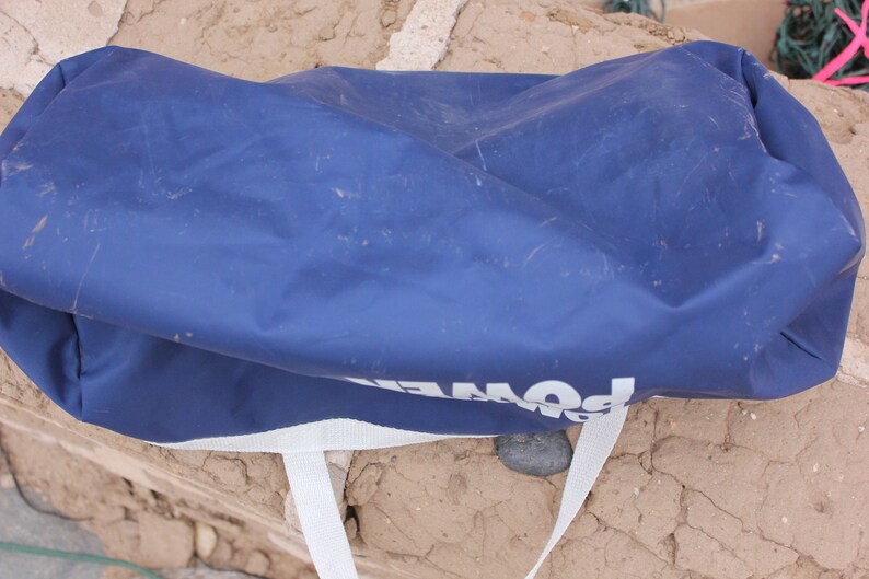 May include: A blue, canvas duffel bag with white straps and the word "POWER" printed on the side.