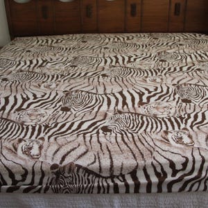 Puede incluir: Una s&aacute;bana con un patr&oacute;n repetitivo de cebras y tigres en color marr&oacute;n y blanco. El dise&ntilde;o muestra m&uacute;ltiples animales superpuestos en la tela, donde las rayas marr&oacute;n oscuro de las cebras y los patrones de pelaje de tigre crean un efecto visual denso.