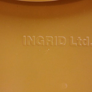Op de afbeelding: Close-up van een gele plastic container met de tekst "INGRID Ltd." gegraveerd op de bodem.