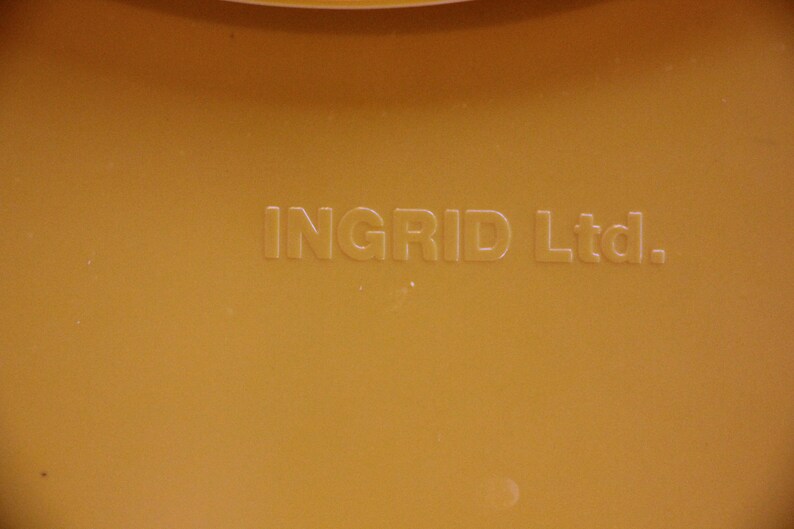 Op de afbeelding: Close-up van een gele plastic container met de tekst "INGRID Ltd." gegraveerd op de bodem.