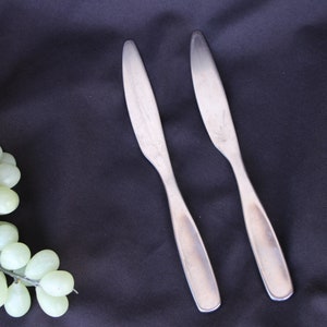 May include: Two silver dinner knives on a black background.