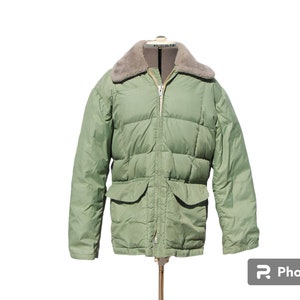 May include: A green puffer jacket with a faux fur collar. The jacket has a zipper closure and two flap pockets.