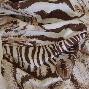 Puede incluir: Una s&aacute;bana bajera con un patr&oacute;n de rayas de cebra en marr&oacute;n y blanco. La tela tiene una textura suave y plegada con un borde el&aacute;stico visible en el lateral, mostrando un dobladillo limpio y un dise&ntilde;o estampado consistente en la superficie.