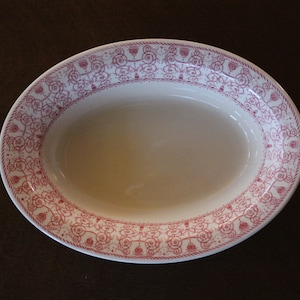 May include: A white oval serving dish with a pink floral pattern around the rim.