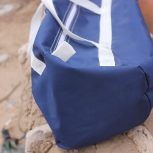 May include: A blue and white duffel bag with white straps. The bag is made of a durable, water-resistant material.