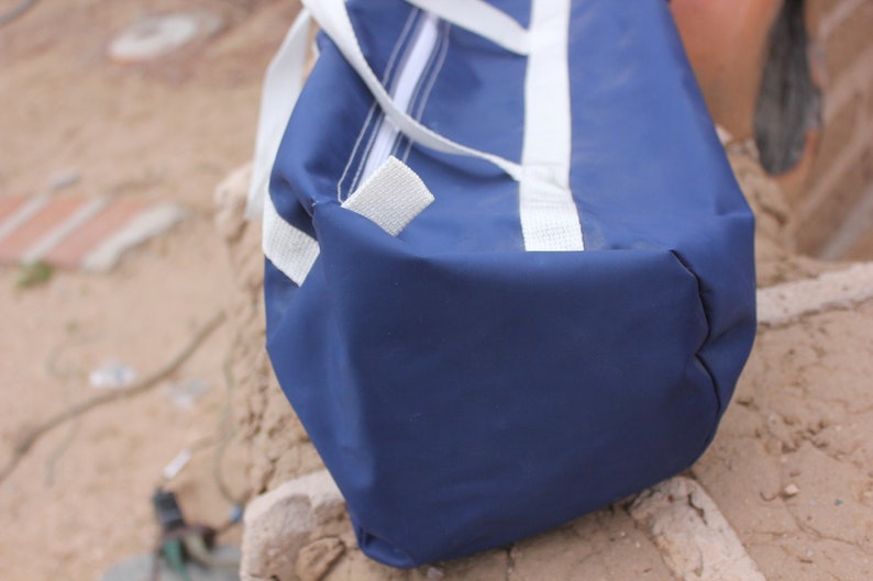 May include: A blue and white duffel bag with white straps. The bag is made of a durable, water-resistant material.