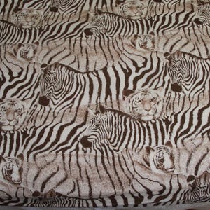 Puede incluir: Una tela con un patr&oacute;n repetitivo de cebras y tigres en marr&oacute;n y blanco. El dise&ntilde;o muestra m&uacute;ltiples cebras en varias posiciones junto a caras de tigres, todo ello en una combinaci&oacute;n de colores marr&oacute;n y blanco consistente.