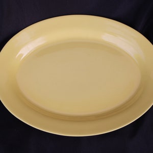 May include: A large, oval-shaped serving platter made of yellow plastic. The platter is smooth and glossy.