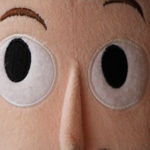 Puede incluir: Primer plano de la cara de un juguete de peluche con cejas marrones y dos ojos grandes blancos con pupilas negras.