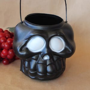 May include: Black plastic Halloween trick-or-treat bucket shaped like a skull with white eyes.