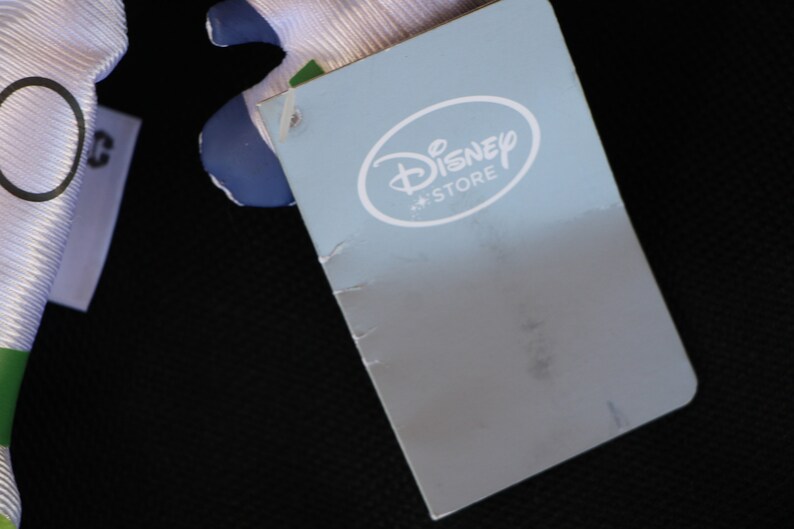 May include: A blue and white tag with the text "Disney Store" in a white circle.