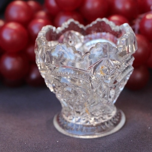 May include: A clear glass bowl with a cut glass design. The bowl has a wide, round base and a flared rim.