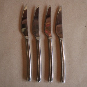 May include: Four silver dinner knives with slightly curved handles.