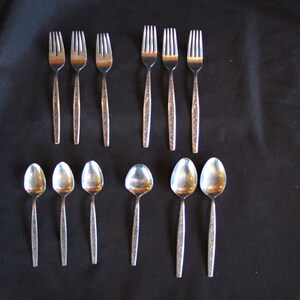 May include: A set of twelve silver-toned forks and spoons. The forks and spoons have a decorative pattern on the handle.