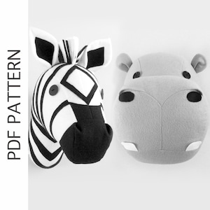 May include: A black and white zebra head and a gray hippopotamus head, both made of fabric, are displayed against a white background. The zebra head has black eyes and a black nose. The hippopotamus head has black eyes and a black nose. Both heads have a button sewn on each side.