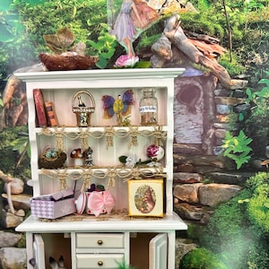 May include: White miniature hutch with a bunny figurine inside, four drawers, and a glass jar with pink flowers. The hutch has a top shelf with books, a basket, a butterfly, and a bottle labeled "Fairy Wishes".