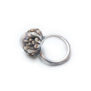 May include: A silver ring with a textured, organic-shaped design. The ring is made of metal and has a silver finish.