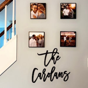 Pu&ograve; includere: Quattro fotografie incorniciate di coppie sono esposte su una parete grigio chiaro. Sotto le foto, un cartello nero in corsivo recita "the Carolans". Le foto sono quadrate e hanno cornici marrone scuro.