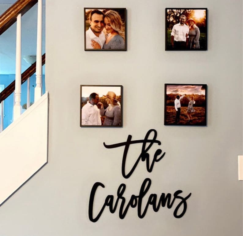 Pu&ograve; includere: Quattro fotografie incorniciate di coppie sono esposte su una parete grigio chiaro. Sotto le foto, un cartello nero in corsivo recita "the Carolans". Le foto sono quadrate e hanno cornici marrone scuro.
