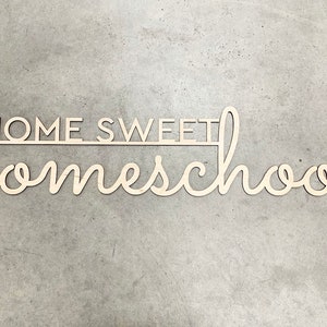 K&ouml;nnte beinhalten: Helles Holzschild mit dem Schriftzug "HOME SWEET homeschool" in Schreibschrift. Das Wort "HOME SWEET" ist in Blockschrift gehalten. Ein dekoratives Element f&uuml;r das Kinderzimmer oder den Arbeitsbereich.