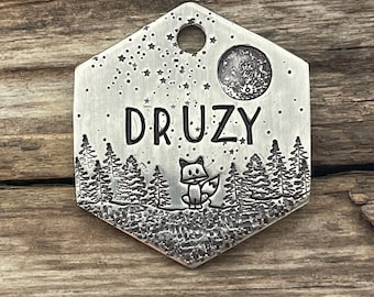 May include: Silver hexagonal pet tag with a fox silhouette, a full moon, and stars engraved on it. The tag reads "Druzy".