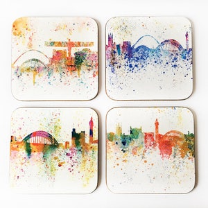 Op de afbeelding: Set van vier vierkante onderzetters met aquarel stadsgezichten van Newcastle, Engeland. Elke onderzetter heeft een ander kleurenschema met verfspatten en een witte achtergrond.
