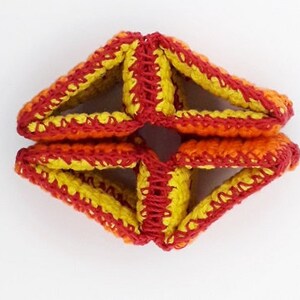 May include: A crocheted geometric starburst in shades of red, orange, and yellow.