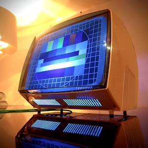 Könnte beinhalten: Ein Vintage-Fernseher mit einem weißen Kunststoffgehäuse und einem blauen Bildschirm, auf dem ein Testmuster angezeigt wird. Der Fernseher steht auf einem Tisch mit einer Lampe im Hintergrund.