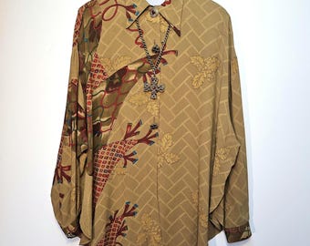 May include: A tan button-down shirt with a unique pattern and a silver cross pendant necklace. The shirt features a geometric design and floral accents in shades of brown, red, and green. The shirt is hanging on a wooden hanger.
