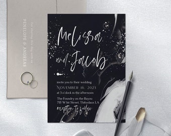 Puede incluir: Invitación de boda en blanco y negro con los nombres "Melissa y Jacob" en escritura elegante. La invitación incluye la fecha y hora de la boda. También se ven un sobre, anillos y una pluma.