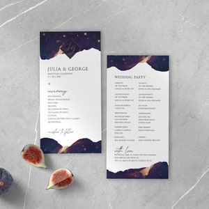 May include: Wedding ceremony programs with a dark blue and gold celestial design. The programs include the names "Julia & George", ceremony details, and wedding party information. Fresh figs are placed near the programs on a gray surface.