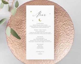 Op de afbeelding: Een trouwmenukaart met een gouden hemels ontwerp, met een halve maan en sterren. Het menu bevat canapés, hors d'oeuvres, voorgerechten en dessertopties. De kaart ligt op een roségouden bord, met eucalyptusbladeren op de achtergrond.