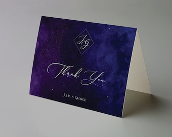 Puede incluir: Tarjeta de agradecimiento plegada con un diseño de galaxia azul oscuro y púrpura. La tarjeta presenta las palabras "Thank You" en escritura elegante, junto con los nombres "Julia & George" y un monograma en forma de diamante.