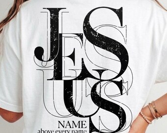 Camiseta cristã com o nome de Jesus acima de todo nome (PNG), Filipenses 2:9-11, tipografia vintage da fé, estampa ousada de Jesus nas costas, design com versículo bíblico.
