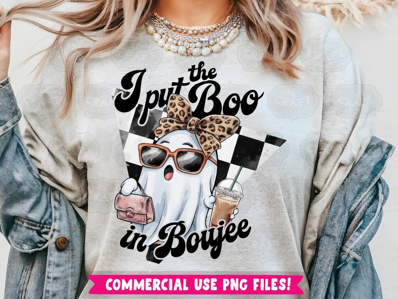 May include: A gray t-shirt with the text "I put the Boo in Boujee" in black and white lettering. A cartoon ghost wearing sunglasses and a leopard print headband is holding a pink purse and a cup of coffee. The background is a black and white checkered pattern.