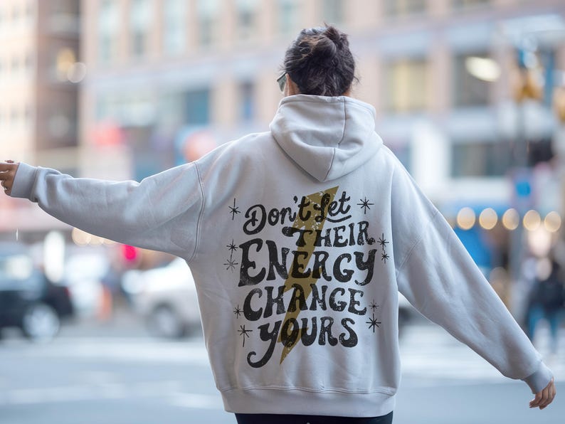 May include: A white hoodie with a black and gold graphic that says "Don't let their energy change yours".